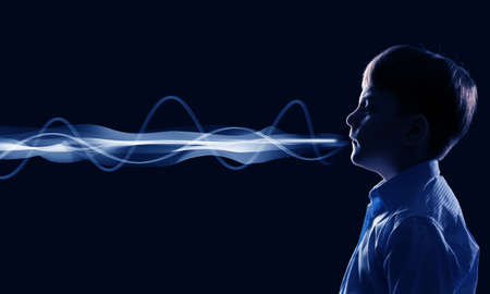 Side view of boy of school age and voice coming out of his mouthの写真素材