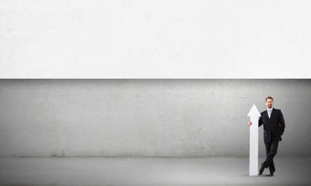 Businessman in suit with white blank arrow in handsの写真素材