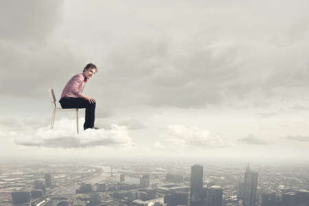 Troubled young man sitting in chair outdoorsの写真素材