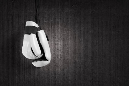 Pair of white boxing gloves hanging on allの写真素材