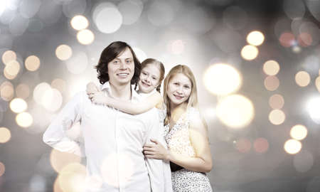 Happy family of mother father and daughter against bokeh backgroundの写真素材