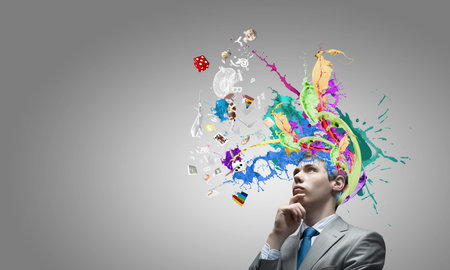 Thoughtful businessman with colorful splashes out of his headの写真素材