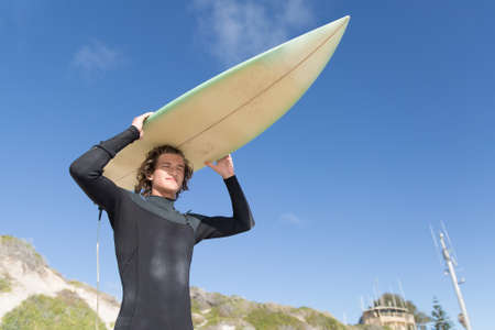 A surfer with his surfboard at the beachの写真素材