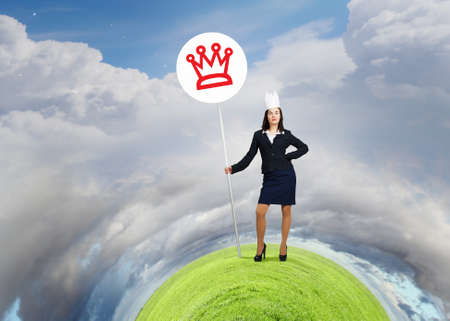 Young businesswoman in paper crown and sign in handsの写真素材