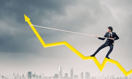 Businessman pulling arrow with rope and making it raise upの写真素材