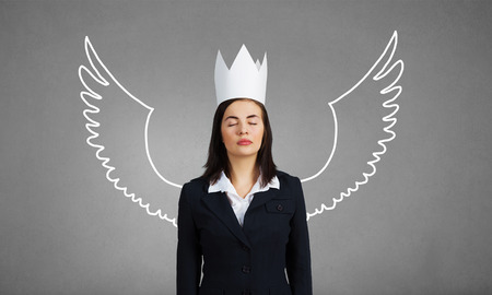 Young businesswoman in crown and with drawn wings behind backの写真素材