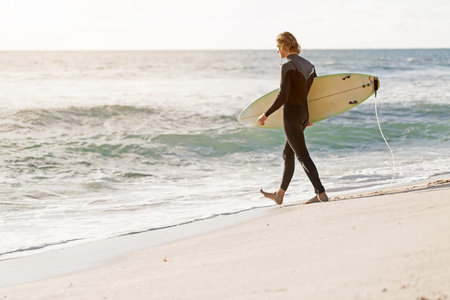 A surfer with his surfboard at the beach