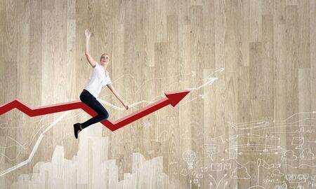 Young businesswoman riding graph arrow going upの写真素材