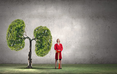 Blond woman in red coat with axe and green treeの写真素材