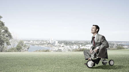 Young handsome businessman riding three wheeled bicycleの写真素材