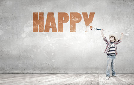 Boy of school age painting wall with brushの写真素材