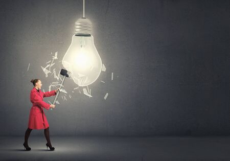 Rear view of woman in red coat with hammer in handsの写真素材