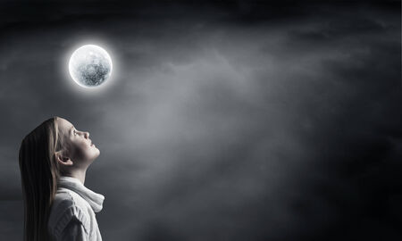 Cute girl of school age against night backgroundの写真素材