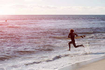 A surfer with his surfboard at the beachの写真素材