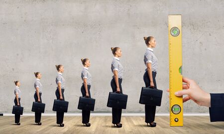 Close up male hand measuring miniatures of businesspeopleの写真素材