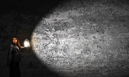 Young pretty businesswoman with lantern in darknessの写真素材