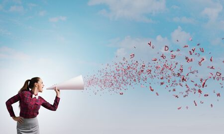 Young pretty woman screaming in paper trumpetの写真素材