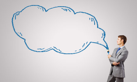 Young businessman holding paint brush and paintings on wallの写真素材