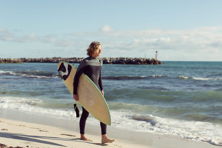 A surfer with his surfboard at the beach