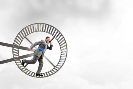Young businessman running in huge hamster wheelの写真素材