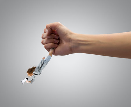 Giant human hand holding miniature of businesswomanの写真素材