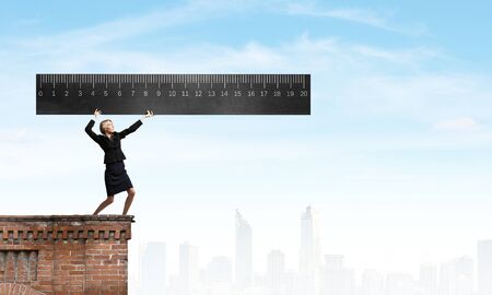Young businesswoman measuring something with big rulerの写真素材