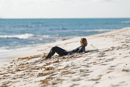 A surfer relaxing and lying on his surfboard at the beach