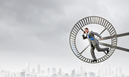 Young businessman running in huge hamster wheelの写真素材