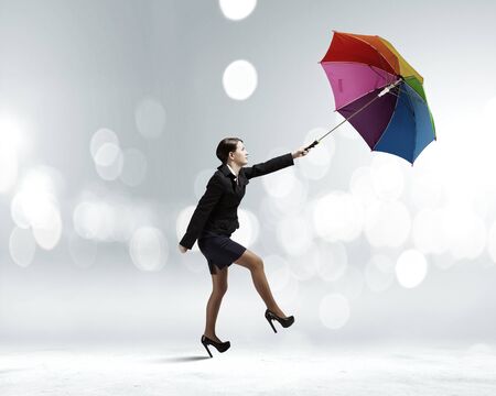 Young businesswoman walking on roof with colorful umbrellaの写真素材