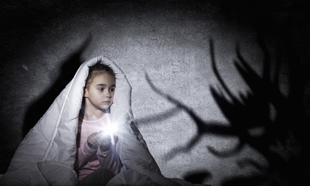 Cute girl in bed under blanket with flash lightの写真素材