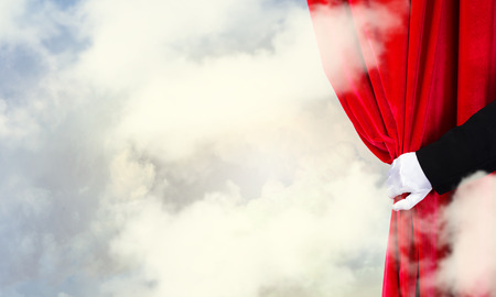 Hand of businessman opening red velvet curtainの写真素材