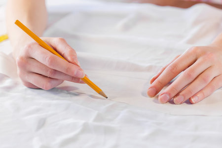 close up of dressmaker at work making patterns of fabric