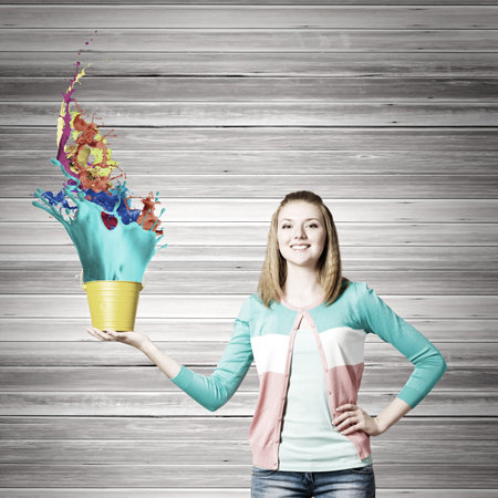 Young woman in casual holding yellow bucket with splashes