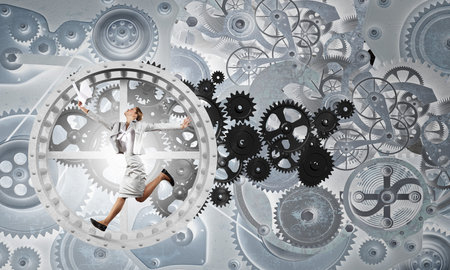 Young businesswoman running in wheel of gears mechanism