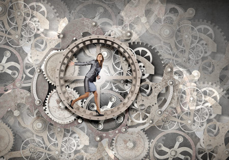 Young businesswoman running in wheel of gears mechanism