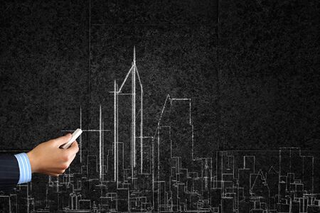 Close up of hand drawing urban city building on chalk boardの写真素材