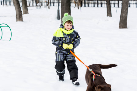 Kid of school age with dog in winter parkの写真素材