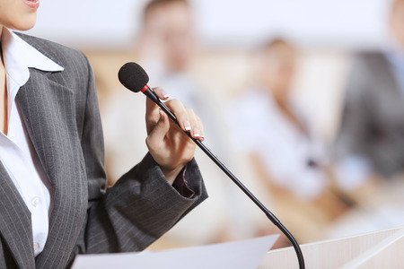 Businesswoman standing on stage and reporting for audience