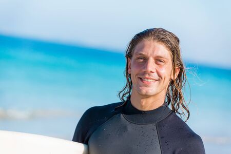 A young surfer with his board on the beachの写真素材