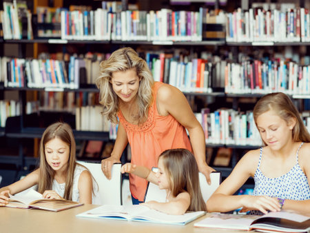Little girls with their mother reading books in libraryの写真素材
