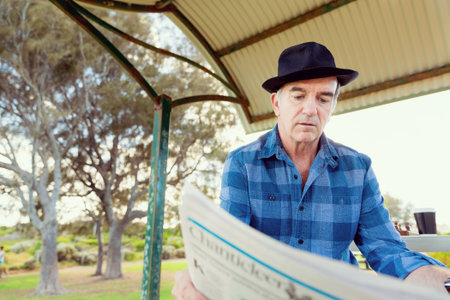 Senior gentleman reading newspaper in park