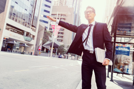 Businessman trying to catch a taxi in business cuty districtの写真素材