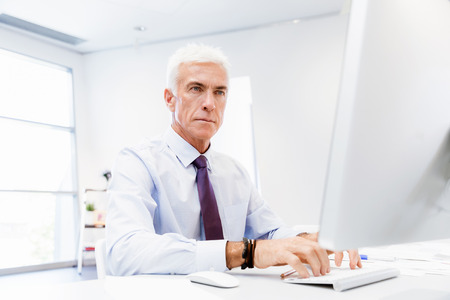 Businessman sitting in office working with computerの写真素材