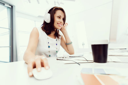 Woman in headphones sitting at desk in office