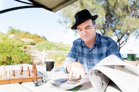 Senior gentleman reading newspaper in parkの写真素材