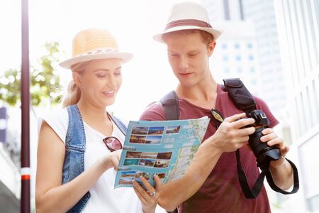 Happy young couple as tourists with a mapの写真素材