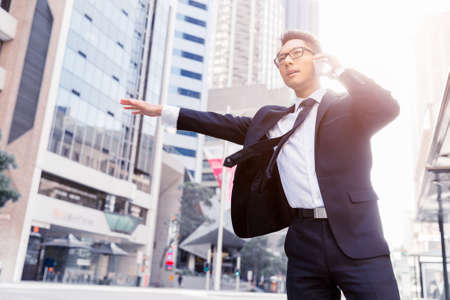 Businessman trying to catch a taxi in business cuty districtの写真素材