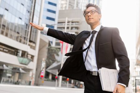 Businessman trying to catch a taxi in business cuty districtの写真素材