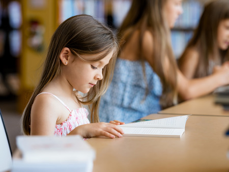Little girls reading books in libraryの写真素材