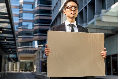 Businessman in a city street holding a blank bannerの写真素材